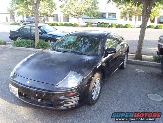 Black Mitsubishi Eclipse coupe with faded paint, parked in a lot. Front-left view