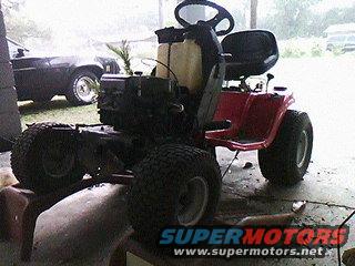 Red riding mower on blocks, engine visible