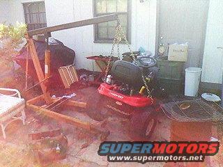 Riding mower lifted by an engine hoist in a yard