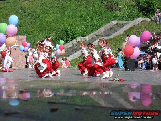 Dancers in red and white costumes perform with balloons