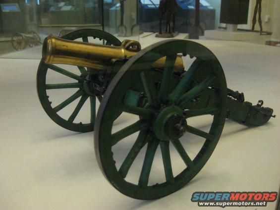 Green wheeled cannon with brass barrel on display