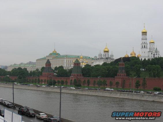 Moscow Kremlin complex with golden domes and red brick walls, viewed across the Moskva River