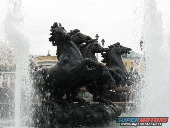 Bronze sculpture of four horses in a fountain with water spraying