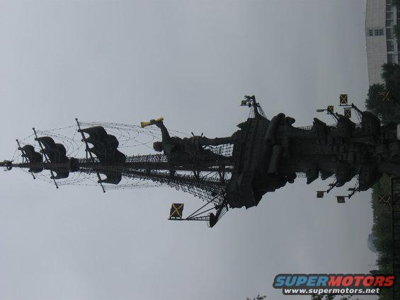 Monumental sculpture resembling a ship with figures against a cloudy sky