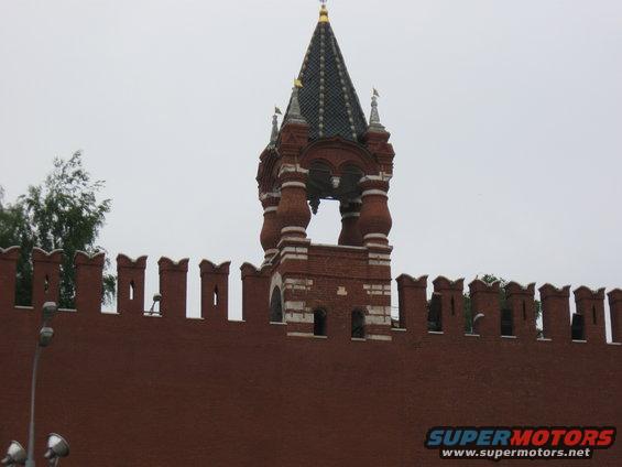 Red brick wall and tower with green tiled roof