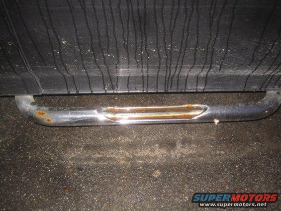 Rusted chrome step bar attached to the side of a vehicle
