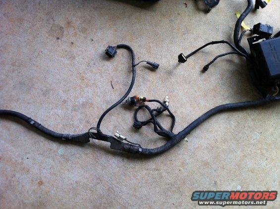 Vehicle wiring harness laid out on a concrete floor. It has multiple connectors and a black box