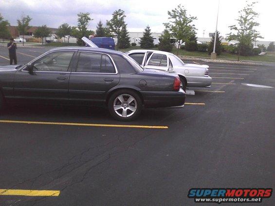 Dark gray 2003 Ford Crown Victoria parked next to a silver sedan, side view