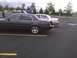 2003 Ford Crown Victoria - Two sedans are parked in a lot under an overcast sky.