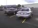 2003 Ford Crown Victoria - Two Ford Crown Victorias are parked side-by-side in a parking lot with a large building in the background.