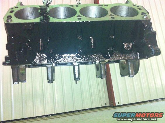 Black engine block with four cylinders visible, suspended by a chain