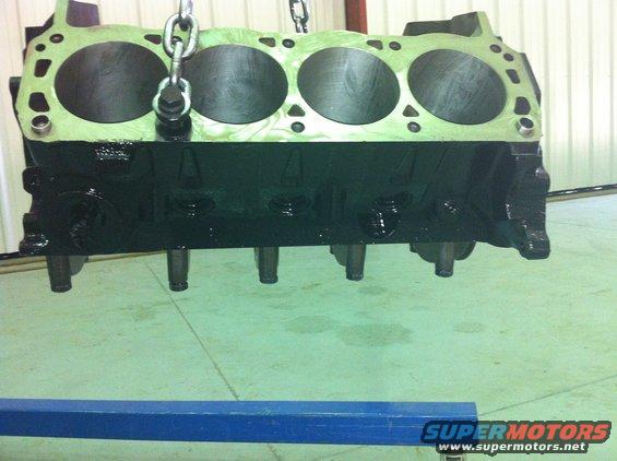 Engine block hanging from chains, showing cylinder bores