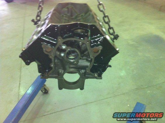 Black engine block suspended by chains, supported by a blue engine stand