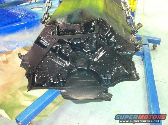 Black engine block suspended by chains on an engine stand
