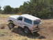 1996 Ford Bronco - This lifted Ford Bronco navigates a rough, off-road terrain under a clear sky.