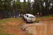 1996 Ford Bronco - A white Ford Bronco navigates a muddy off-road course with trees in the background.