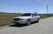 2008 Mercury Grand Marquis - A gold Mercury Grand Marquis is parked on the shoulder of a road with fields in the background.