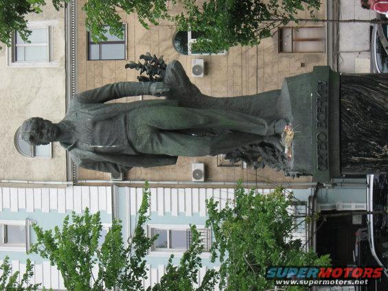 Statue of a man holding flowers in front of a building