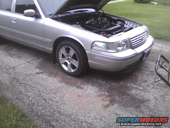 Silver 2003 Ford Crown Victoria with hood open, showing engine. Front 3/4 view