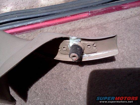 Interior trim piece with a rubber bumper attached to a metal bracket, showing signs of repair with adhesive