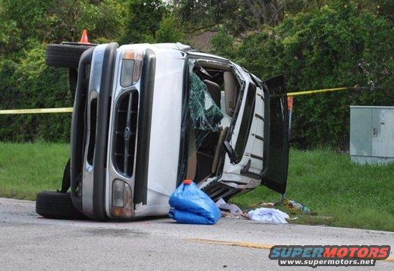 White SUV flipped on its side on the side of the road, windshield cracked