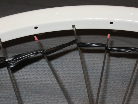 White bicycle wheel rim with spokes wrapped in black tape