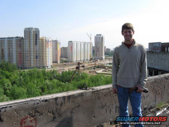 Man on rooftop overlooking construction site and apartment buildings