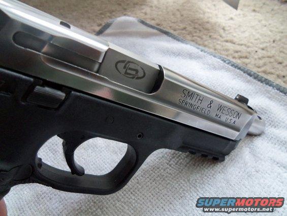 Silver and black Smith & Wesson pistol slide with engraved logo and text, resting on a cloth