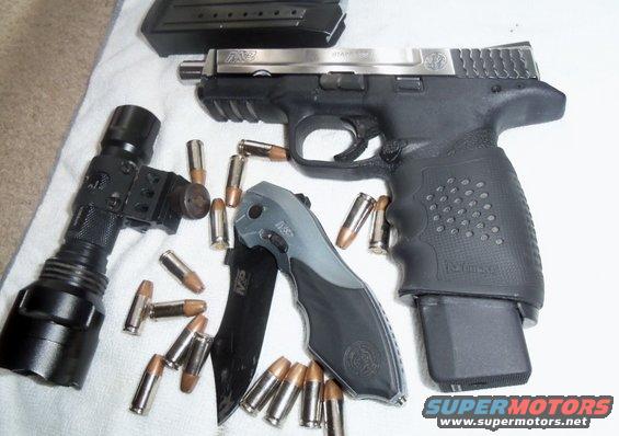 Handgun with extended magazine, tactical knife, flashlight, and loose ammunition