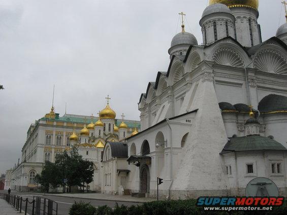Moscow Kremlin cathedrals with golden domes and white walls under a cloudy sky