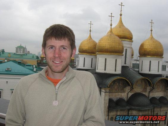 Man in front of golden domed building with Supermotors logo