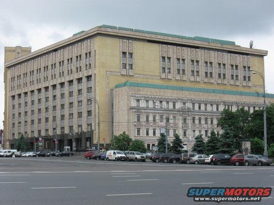 Parked cars in front of a large, multi-story building