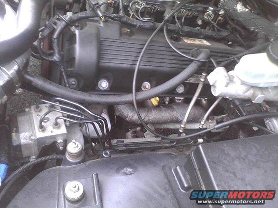 Close-up view of a car's engine bay, showing the engine block, hoses, and wiring