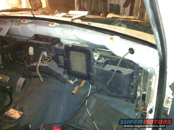 Interior of a vehicle with the dashboard removed, showing exposed wiring and HVAC components