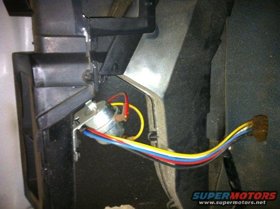 Close-up of a silver switch with red, yellow, blue, and white wires connected, mounted to black plastic interior trim