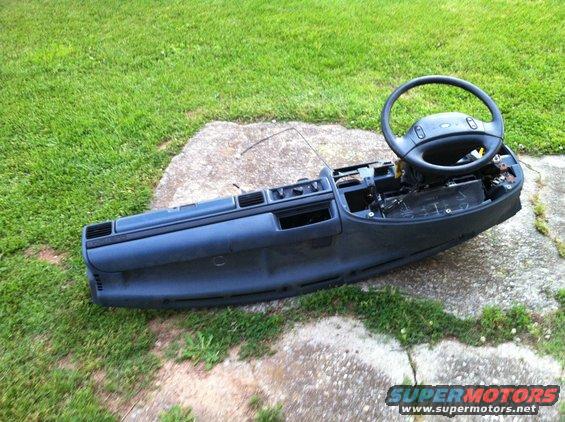 Dark dashboard assembly with steering wheel, removed from vehicle