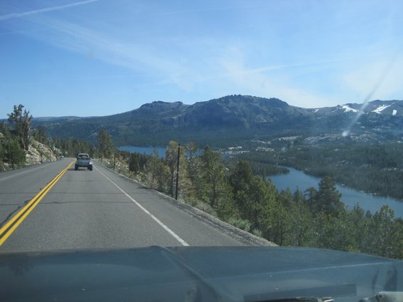 SUV driving on a road with a lake and mountains in the background