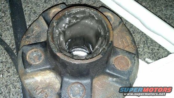 Close-up of a greased wheel bearing assembly with rust and visible bolts