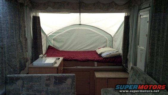 Interior view of pop-up camper with bed, sink, and seating areas