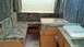 2006 Yugo Vega - The interior of a pop-up camper shows seating, a table, and a small kitchen area with a sink.