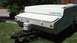 2006 Yugo Vega - A white pop-up camper trailer is parked on a grassy lawn, a propane tank on its trailer hitch.