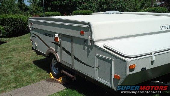 White pop-up camper with Viking branding, parked on grass and a sidewalk