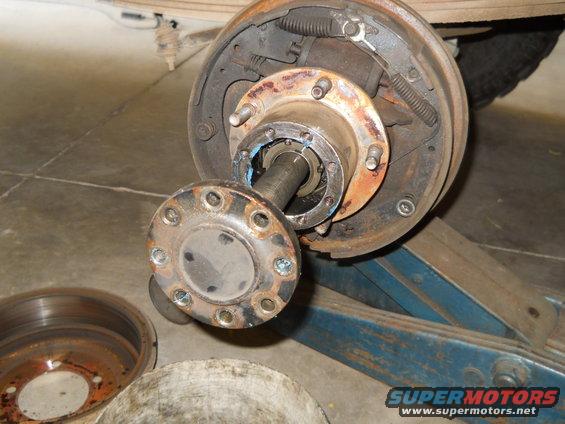 Wheel hub assembly with brake drum removed, showing rotor and axle shaft. A separate brake rotor is visible to the left