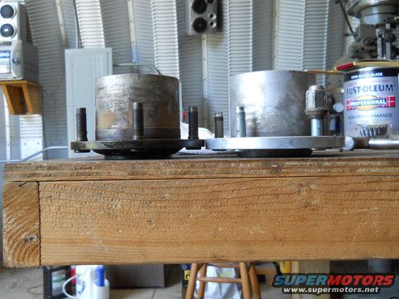 Two metal wheel hubs with bolts on a wooden workbench
