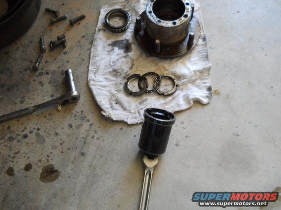 Wheel hub, bearing, and assorted nuts and bolts laid out on a concrete floor with a rag