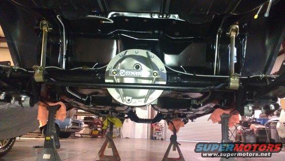 Undercarriage of a vehicle on jack stands, showing a polished differential cover and suspension components
