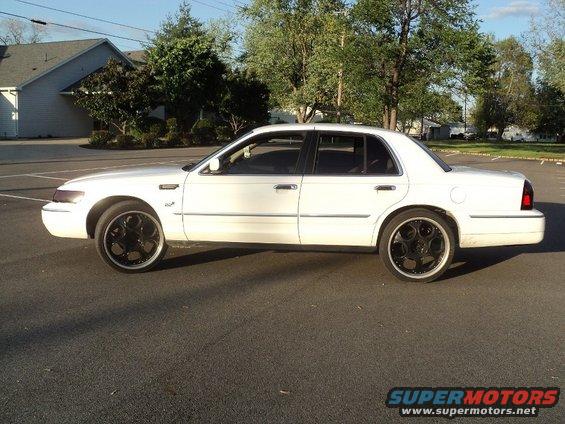 White 2000 Mercury Grand Marquis side view with custom black wheels