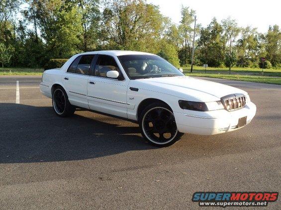 White 2000 Mercury Grand Marquis sedan with black rims, parked on asphalt