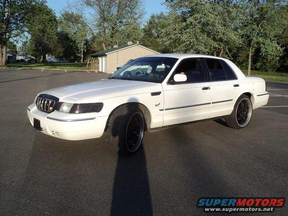 White 2000 Mercury Grand Marquis with black aftermarket wheels parked in a lot