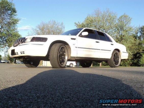 White 2000 Mercury Grand Marquis sedan with aftermarket wheels, viewed from a low angle
